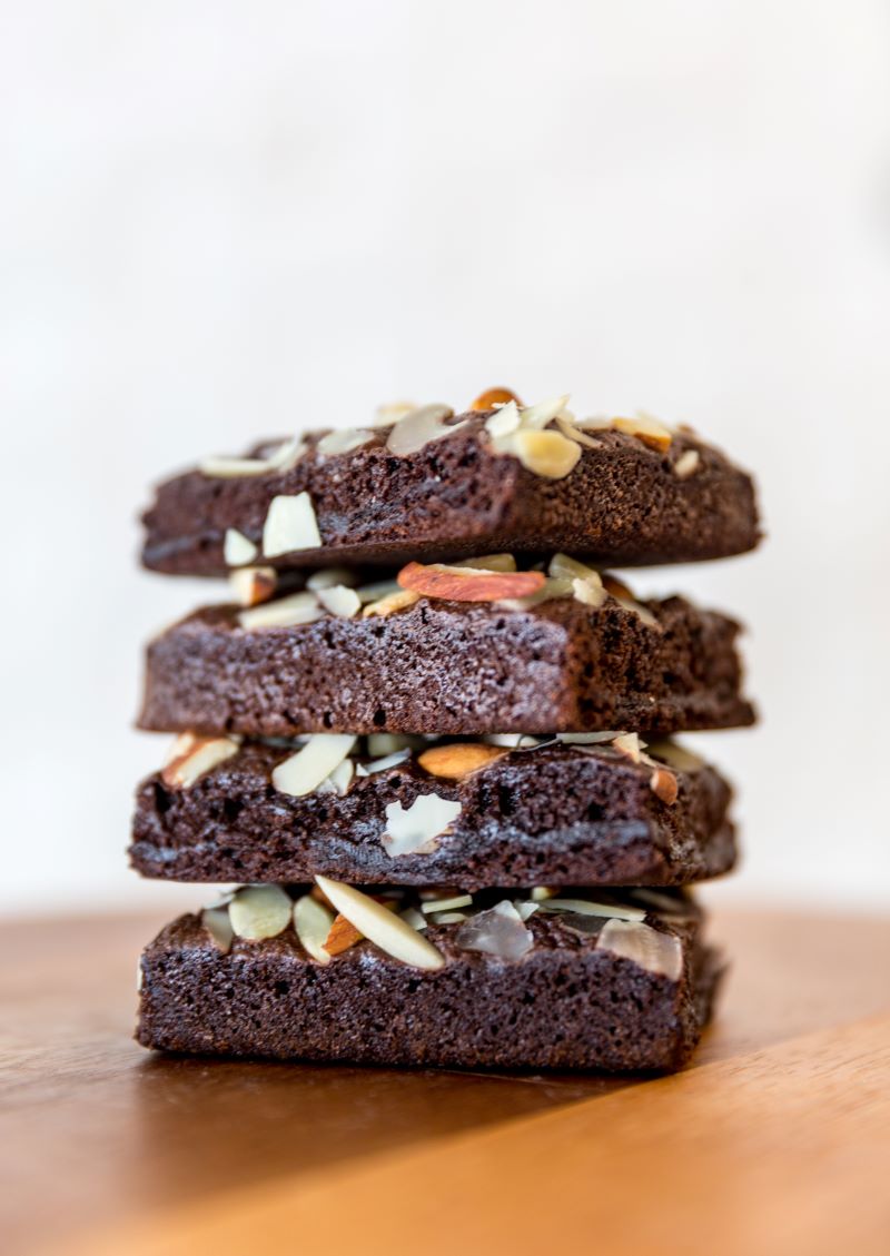 Stack of 4 chocolate almond brownies on a wood table