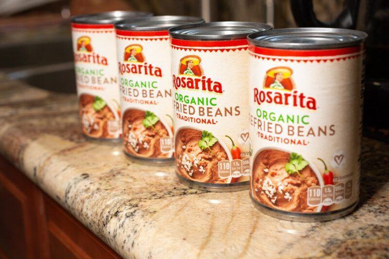 Four cans of refried beans on a table or shelf