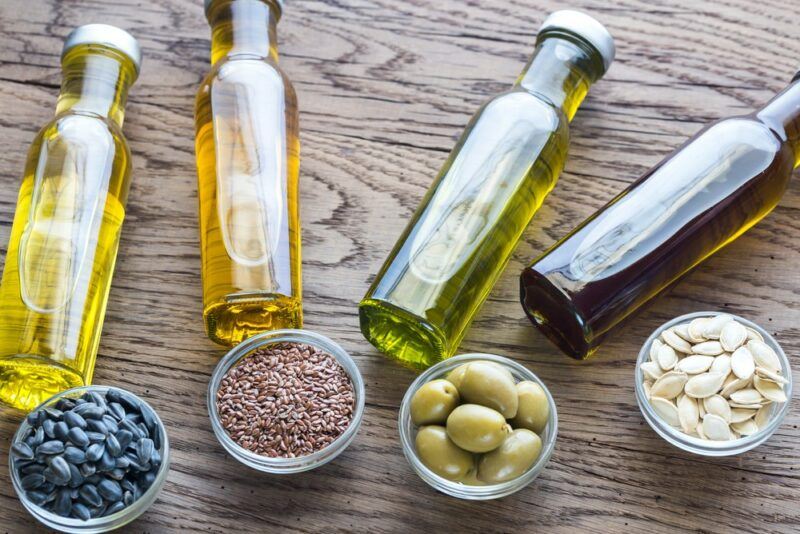 Four different jars of oil, each next to a dish that contains the ingredient used to make it