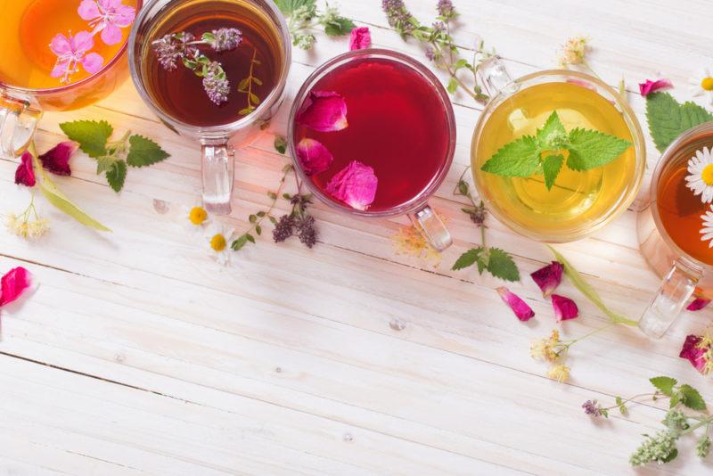 Four colored mugs of flower tea on a white table