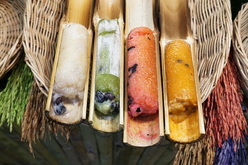 Bamboo tubes containing khao lam of different colors