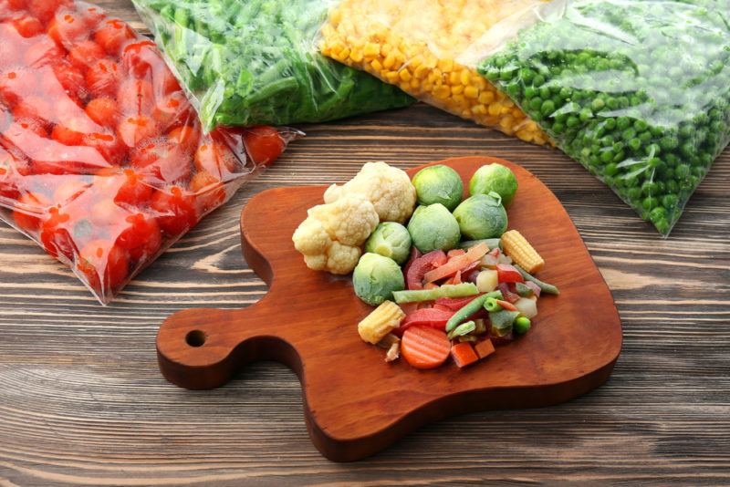 Freezer bags of veggies with vegetables on a cutting board too