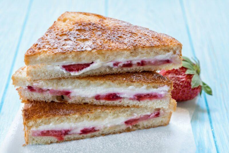 Three triangles of French toast that have been stuffed with cream cheese and strawberries