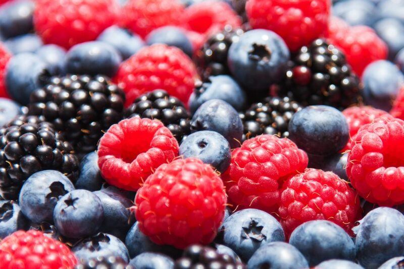 Fresh berries all piled together, including blackberries, raspberries, and blueberries