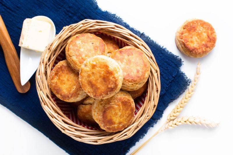 A basket of fresh biscuits on a blue tablecloth