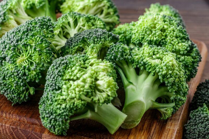 A wooden board with fresh broccoli heads on top