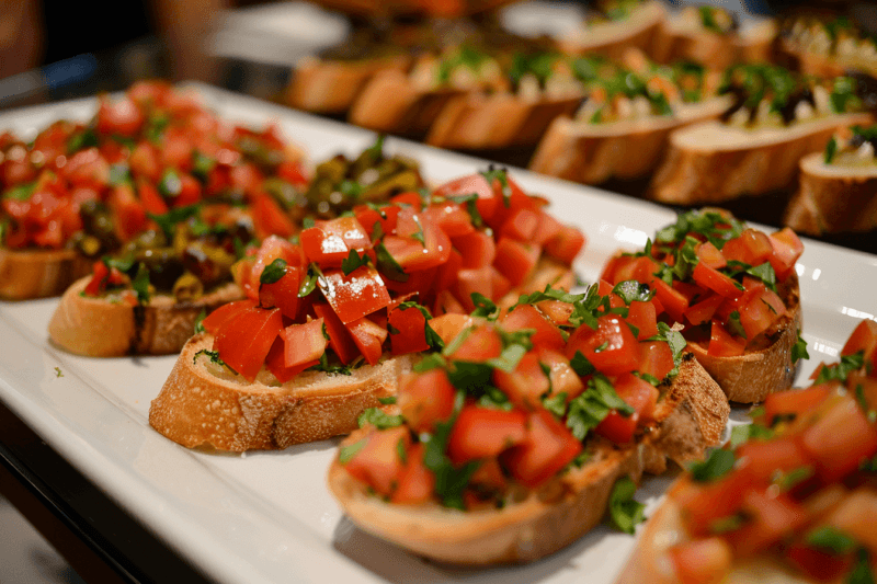 Large plate of bruschetta that are being served at a party.