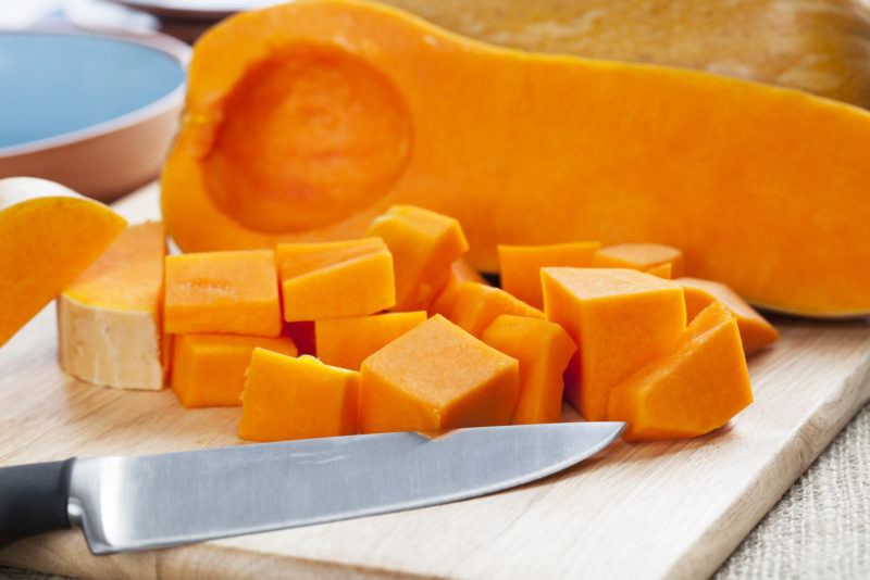 Half a butter nut squash plus cubed ones on a chopping board