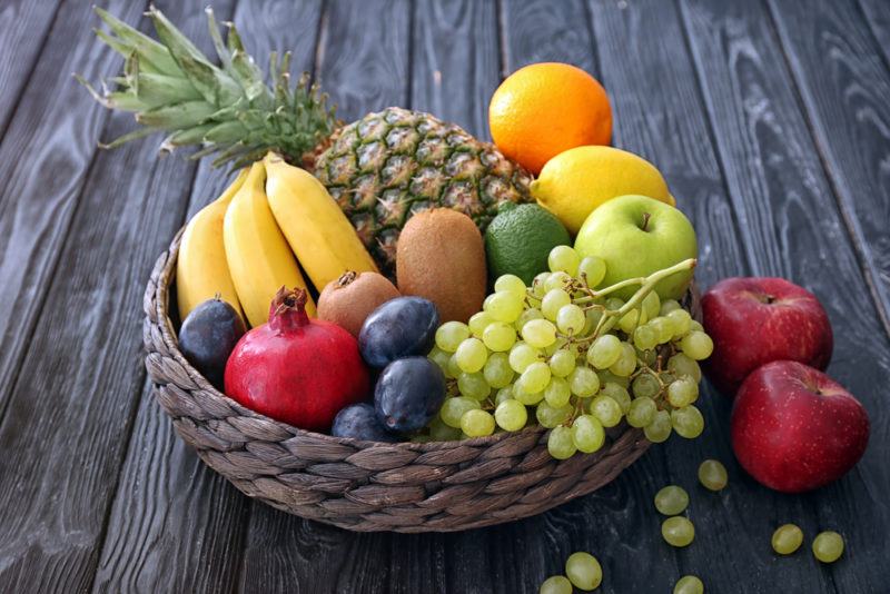 A basket of fresh fruit, including bananas, pineapple, oranges, grapes and more