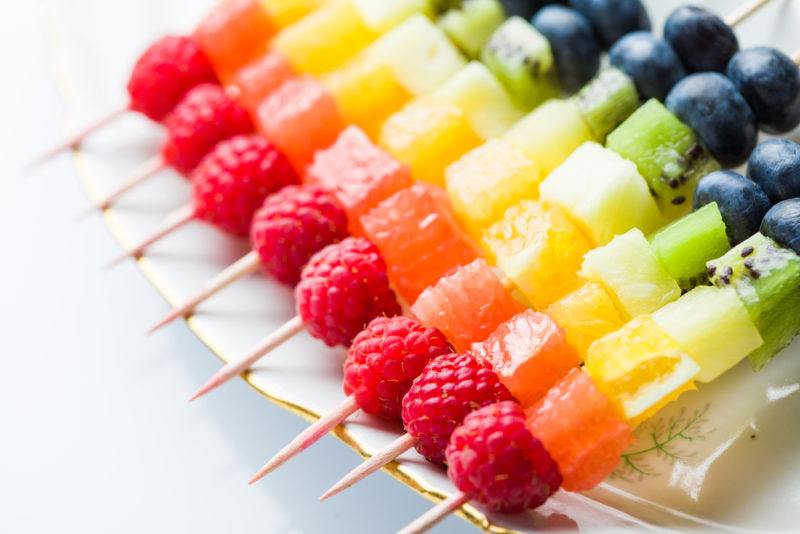 Pieces of fruit on skewers with the colors of the rainbow