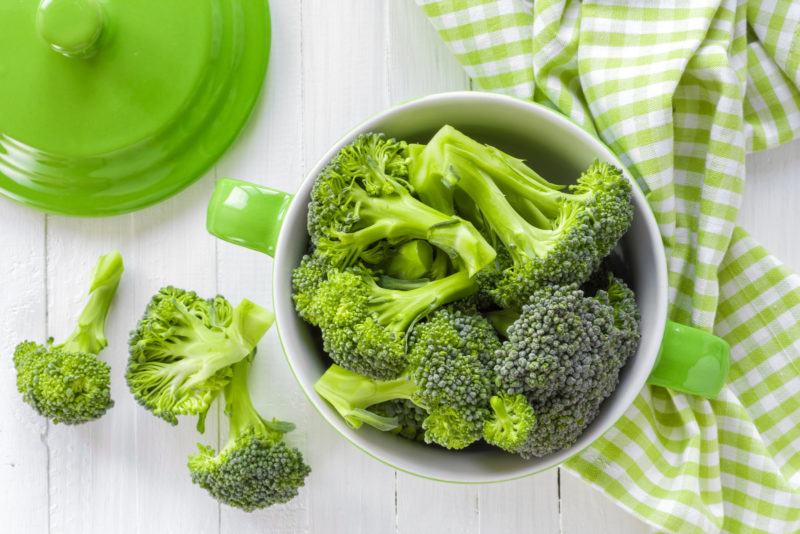 A bowl with a handle filled with broccoli florets