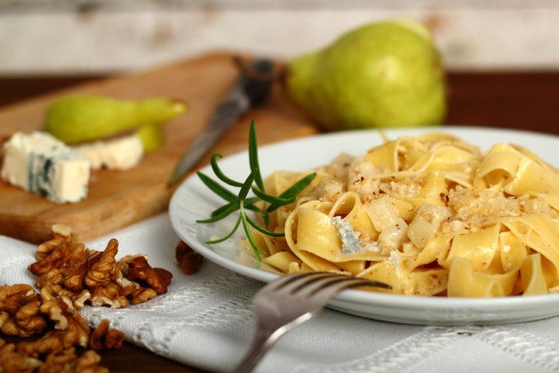 Fresh pasta with blue cheese with a fork, walnuts, blue cheese, and pears