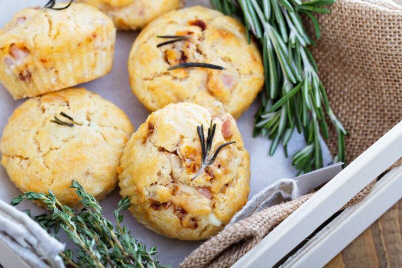 A selection of five fresh savory muffins near some rosemary