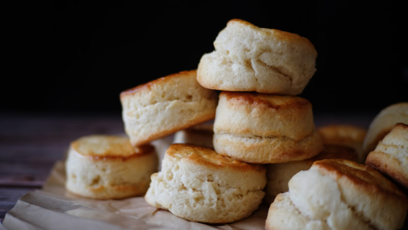 A pile of scones on a table against a black background