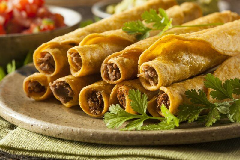 A plate containing rolled fresh taquitos with some herbs for flavor