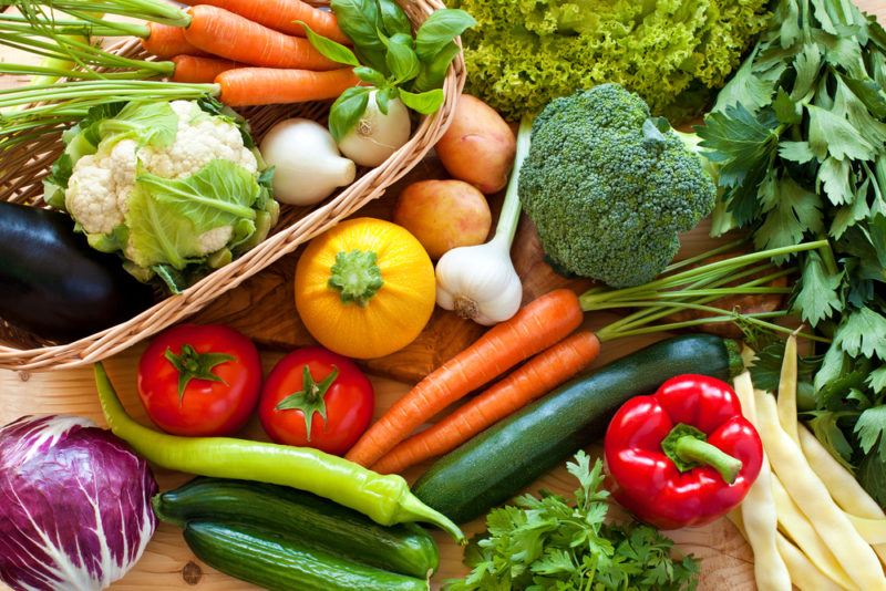 Many fresh vegetables on a table, including broccoli, carrots, and garlic