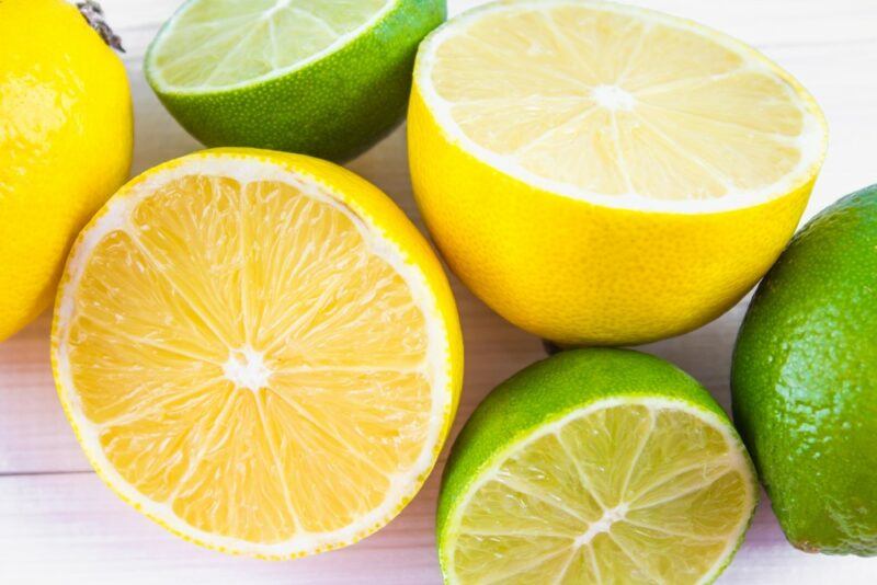 A wooden table with lemon and limes halves, all face up