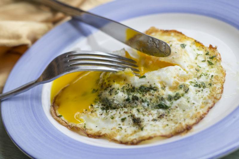 Fried egg over easy on a plate with a knife and fork