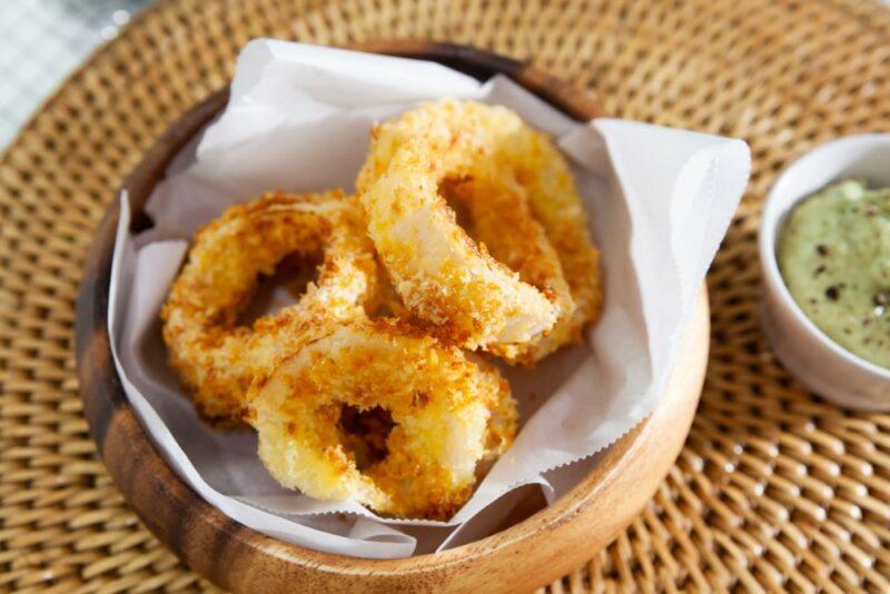 Fried onion rings next to a small container of dip