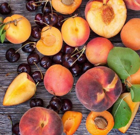 A selection of peaches and cherries on a wooden table