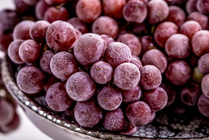 A bowl filled with frozen red grapes