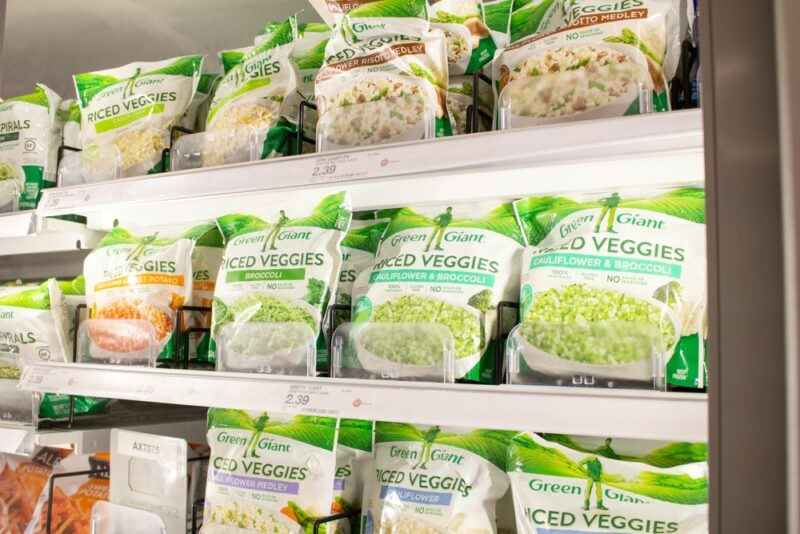 A grocery store freezer containing various types of frozen vegetables