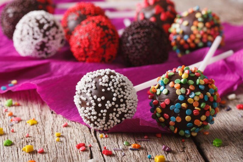 Various cake pops, all with different toppings, including red, white, brown, and rainbow sprinkles