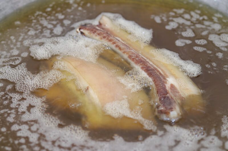 Two pieces of pork belly submerged under liquid