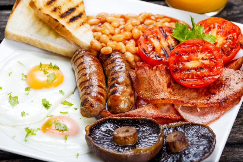 A full english breakfast with eggs, mushrooms, sausages, and other foods