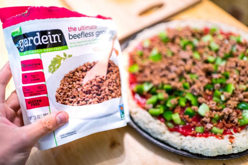 Gardein beefless ground in front of a pizza that uses the ingredient