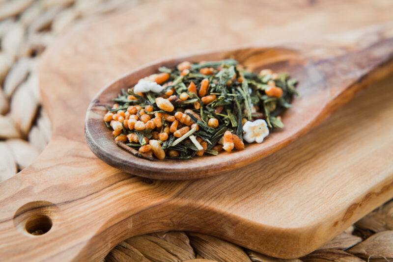 a wooden ladle with Genmaicha tea resting on top of a wooden chopping board