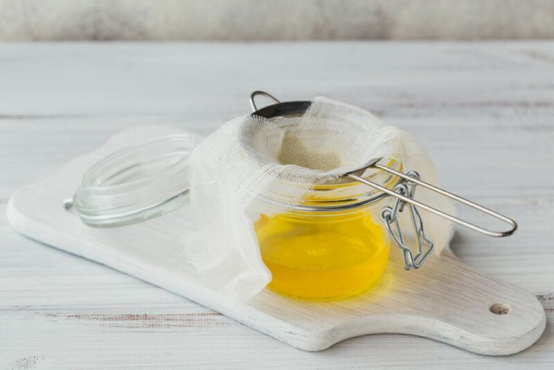 A jar with a cloth where ghee is being strained into it