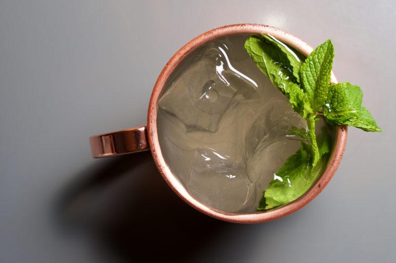 A gin buck cocktail in a copper mug with a peppermint leaf