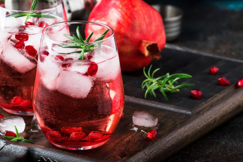 Two gin and tonics with ice and pomegranates