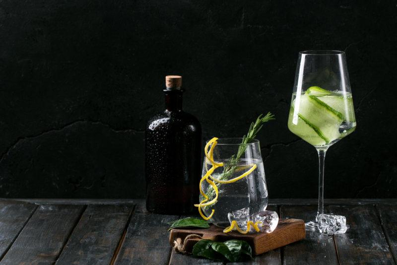 A gin and tonic cockail in two glasses with a bottle of tonic syrup