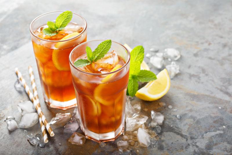 Two glasses with iced tea on a table with ice