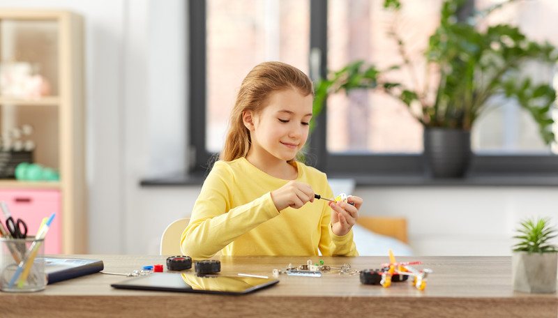 Science Kit of the Month Clubs - Young Girl sitting at desk at home working on a science project