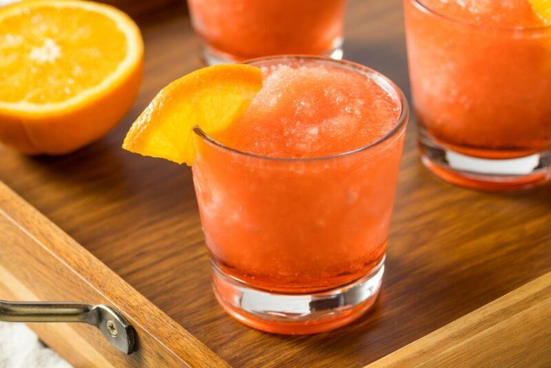 Three glasses containing a slushie orange cocktail called Loretta's punch