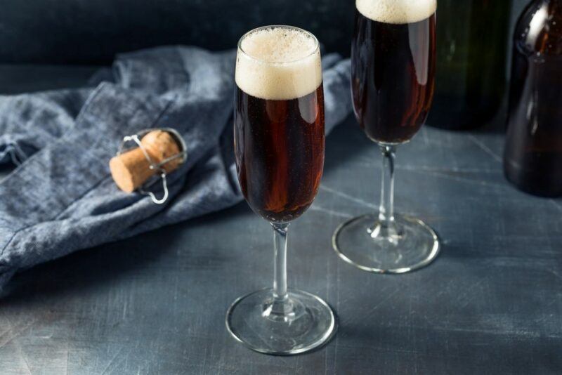 Two glasses containing a red velvet Guinness cocktail on a table, next to a cloth