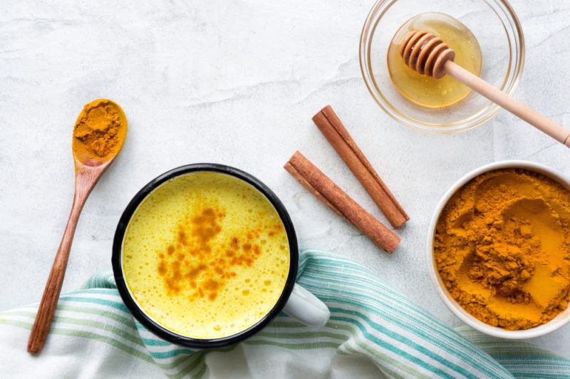 A mug of golden milk with turmeric, cinnamon and honey