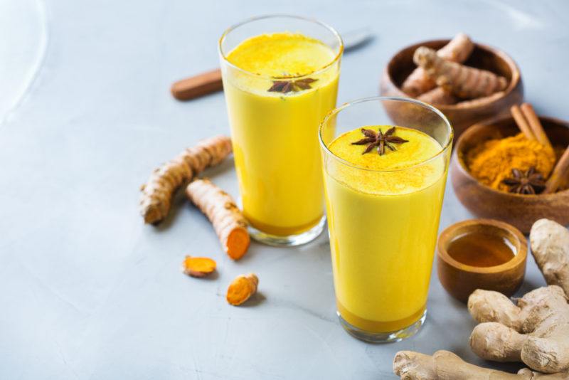 Two glasses of golden milk on a light blue table