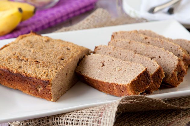 A white oblong plate with half a loaf of banana bread and various sliced pieces 