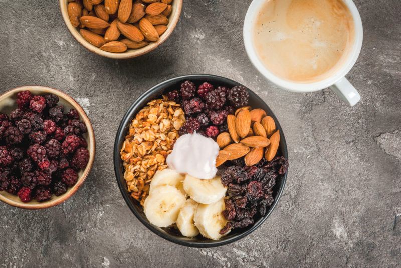 A black bowl with granola and a selection of toppings