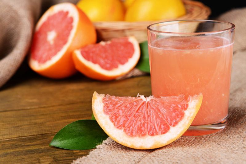 A glass of grapefruit juice with sliced pieces of grapefruit