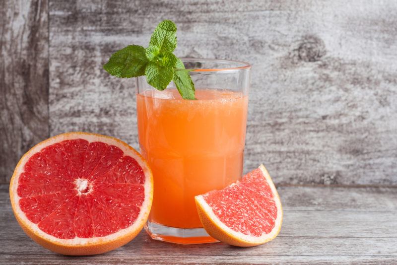 A glass of grapefruit juice with a cut grapefruit on a table