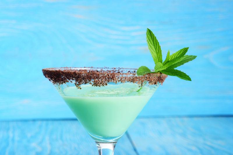 A green grasshopper cocktail in front of a blue background