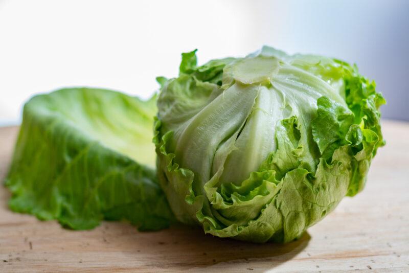 closeup image of a head of Great Lakes lettuce on a wooden surface