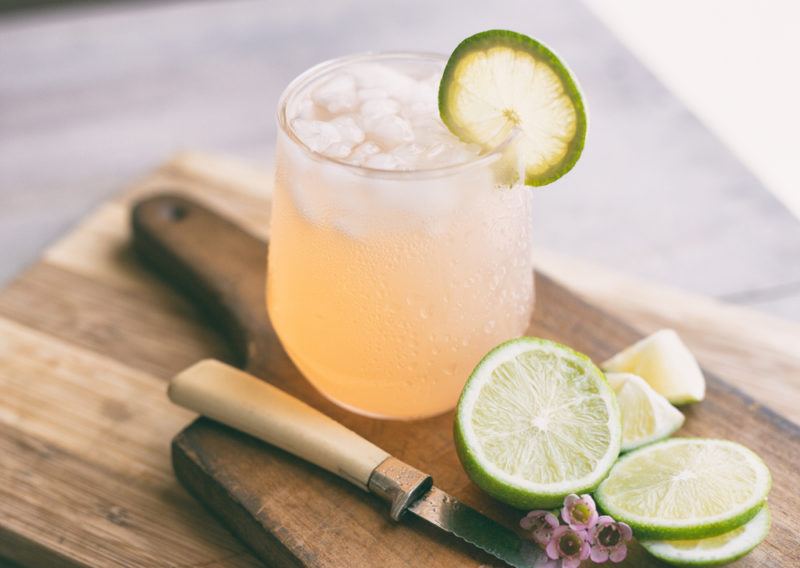 A glass of a Great Gatsby cocktail on a wooden board with slices of lime