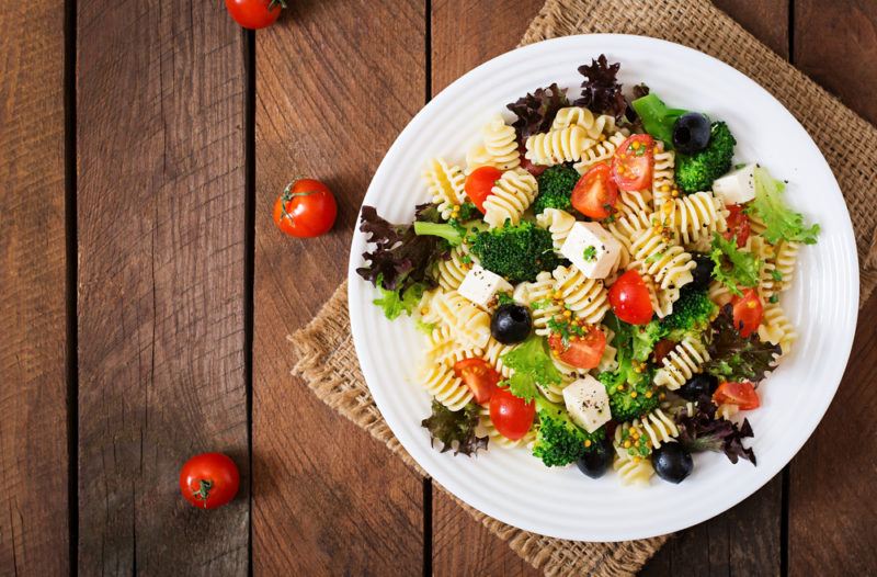 A white plate with a fresh Greek pasta salad