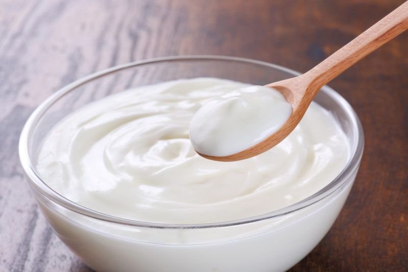 A glass bowl of low fat Greek yogurt with a spoon